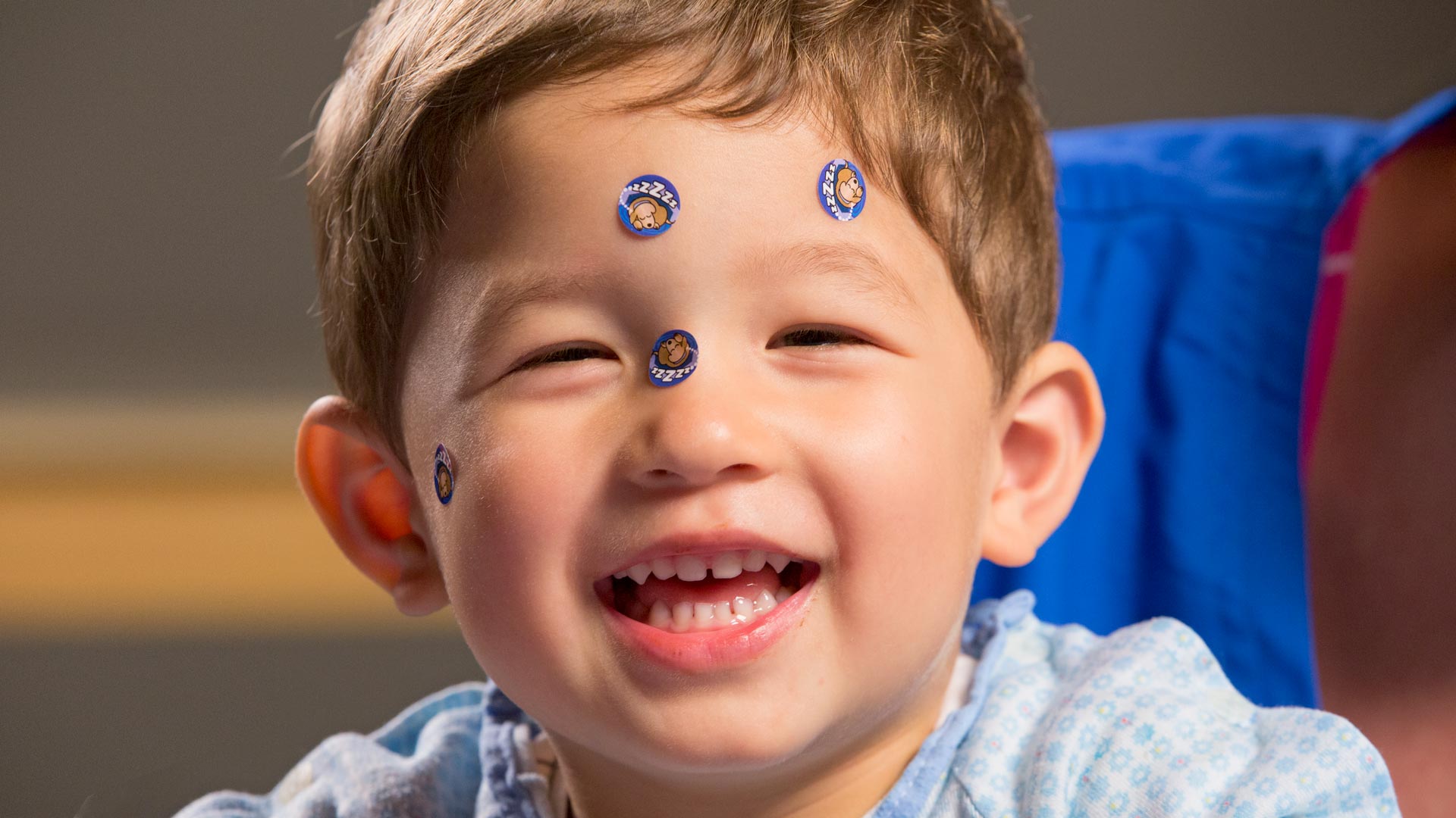 Young boy laughing with puppy stickers on his face