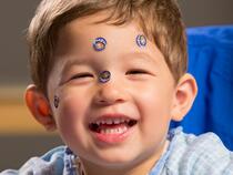 Young boy laughing with puppy stickers on his face